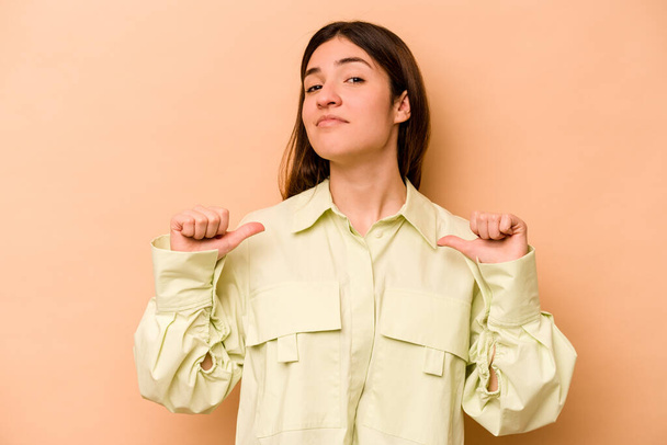 Young hispanic woman isolated on beige background feels proud and self confident, example to follow. - Photo, Image