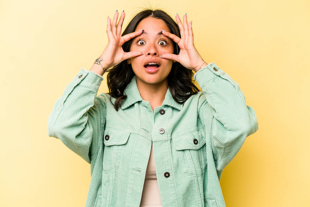 Young hispanic woman isolated on yellow background keeping eyes opened to find a success opportunity. - Photo, Image