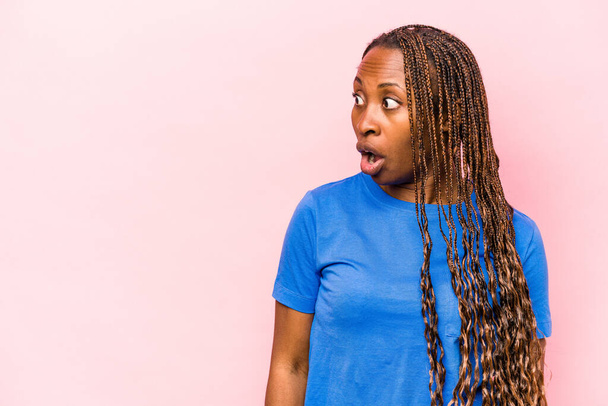 Jeune femme afro-américaine isolée sur fond rose choquée par quelque chose qu'elle a vu. - Photo, image