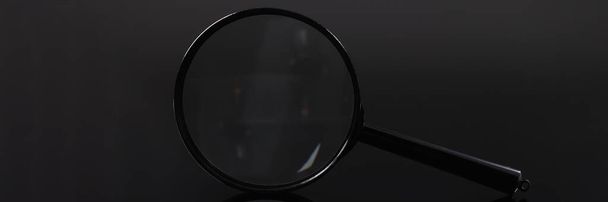 Closeup of magnifying glass on black background - Foto, Imagen