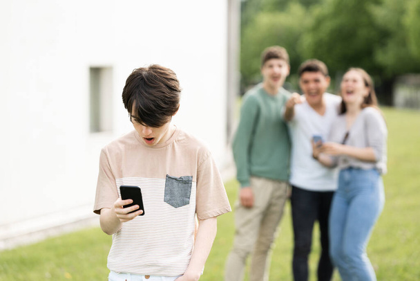 Adolescente niño mirando el teléfono y sufriendo acoso cibernético. - Foto, Imagen
