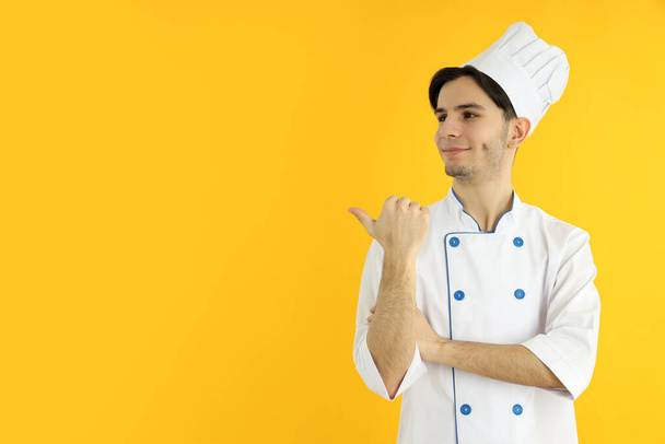 Concept of cooking, young man chef on yellow background - Фото, изображение