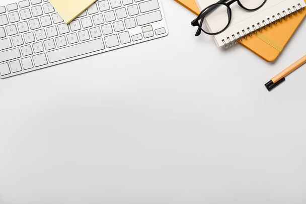 Flat lay draadloos toetsenbord, notebook, bril en pen op witte tafel. Kopieer ruimte voor uw tekst - Foto, afbeelding