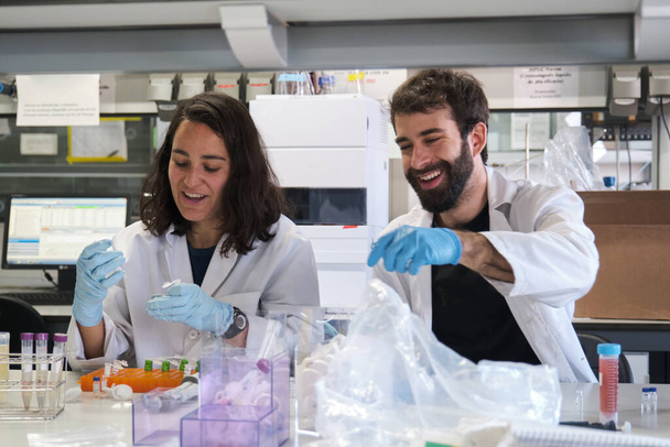 Dos jóvenes estudiantes de doctorado trabajando en un laboratorio real. - Foto, Imagen