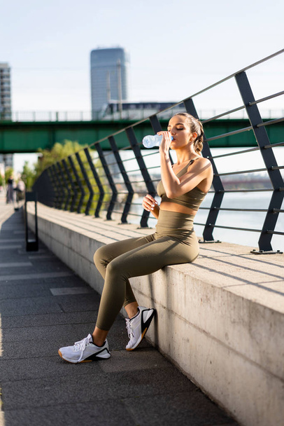 Hübsche junge Frau macht Pause bei Sport auf der Uferpromenade - Foto, Bild