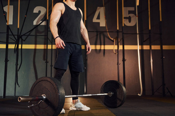 Strong man in sportive clothes lifting barbell in the gym. - Valokuva, kuva
