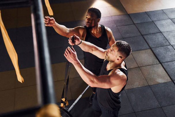 Personal trainer is on job. African american man with white guy have workout day in gym. - Foto, Bild