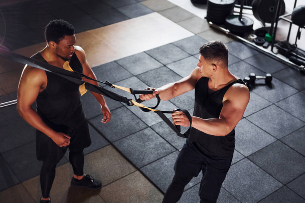 Personal trainer is on job. African american man with white guy have workout day in gym. - Foto, Imagen