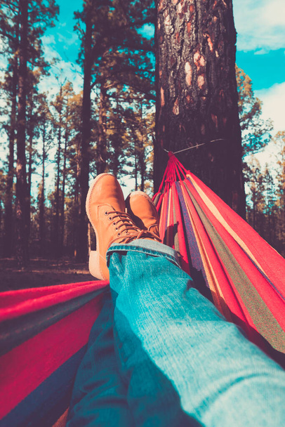 Ноги и гамак расслабиться досуг с лесами и небо на заднем плане - люди наслаждаются окружающей средой и альтернативный свободный образ жизни наслаждаясь природой и альтернативный отдых или выходные в одиночку - Фото, изображение