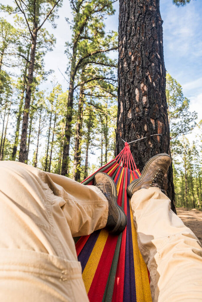 Mężczyźni zrelaksować się na hamaku nogi punkt z wysokich drzew i lasów Forest Park w tle - wolne ludzie korzystających środowiska przyroda i przygoda podróży styl życia - Błękitne niebo i weekend koncepcji wypoczynku - Zdjęcie, obraz