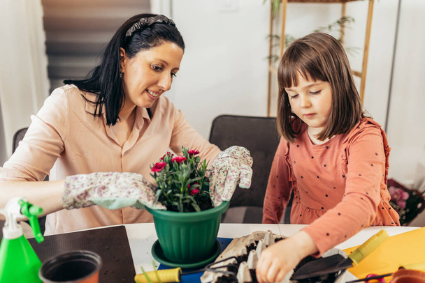 Cute child girl helps her mother to care for plants. - Photo, Image