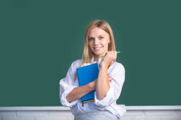Female student on lesson lecture in classroom at high school or college. Creative young smiling female student with pen and book. - Foto, Imagen