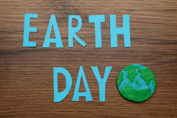 Слова День Земли и пластилиновая планета на деревянном столе, плоский уголок - Фото, изображение