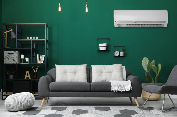Modern air conditioner on green wall in living room with stylish furniture - Photo, Image