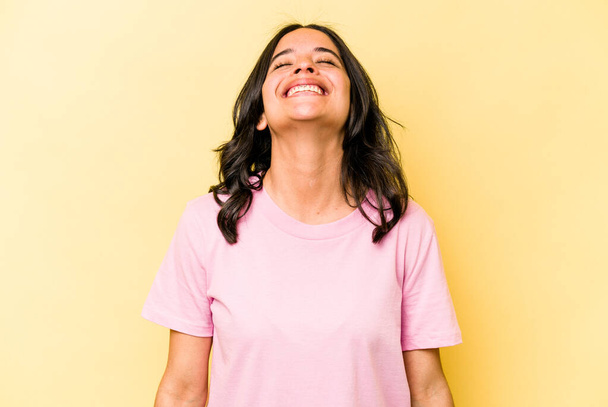 Молода іспаномовна жінка ізольована на жовтому тлі розслаблена і щаслива сміється, шия розтягується, показуючи зуби
. - Фото, зображення