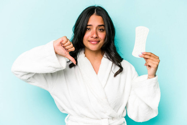 Young caucasian woman holding sanitary napkin isolated on pink background showing a dislike gesture, thumbs down. Disagreement concept. - Photo, Image