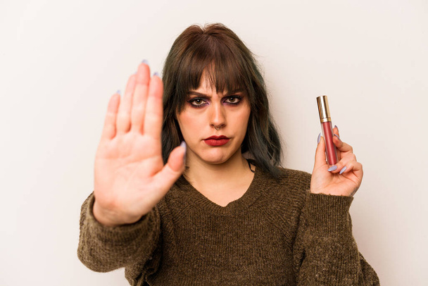 Jonge blanke make-up artiest vrouw met een lipgloss geïsoleerd op witte achtergrond staan met uitgestrekte hand tonen stopteken, voorkomen dat u. - Foto, afbeelding