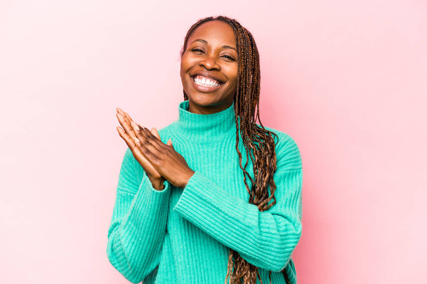 Νεαρή Αφροαμερικάνα γυναίκα απομονωμένη σε ροζ φόντο αισθάνεται ενεργητική και άνετη, τρίβοντας τα χέρια με αυτοπεποίθηση. - Φωτογραφία, εικόνα