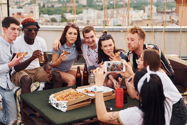 Lezzetli pizzayla. Gündelik giysiler içinde bir grup genç gündüz vakti çatıda parti veriyor.. - Fotoğraf, Görsel