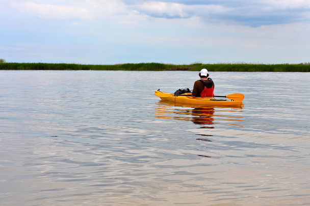 Kayaking. Man paddles a yellow kayak on Danube river. Summer kayaking. Concept for adventure, travel, action, lifestyle - Zdjęcie, obraz