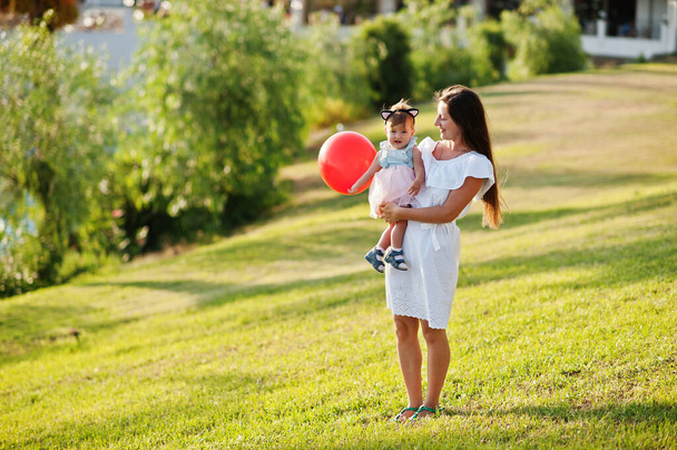 Young mother hold on hands baby girl with balloon at Turkey resort. - Фото, изображение