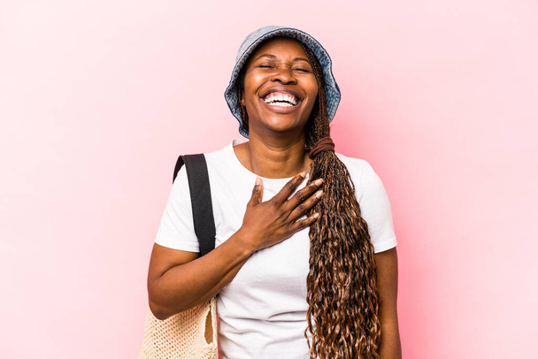 Young African American woman going the beach isolated on pink background laughs out loudly keeping hand on chest. - Photo, Image