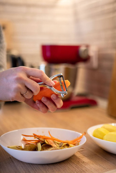 pelando la zanahoria de cerca arrullando en la cocina doméstica - Foto, Imagen