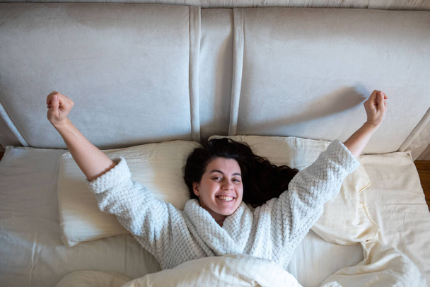 rano w łóżku kobieta budzi się leżąc w łóżku z białymi prześcieradłami jasny pokój - Zdjęcie, obraz