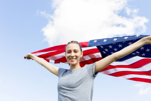 Nuori nainen, jolla on Amerikan lippu. Demonstraatio. Yhdysvaltain lippu taivasta vasten - Valokuva, kuva