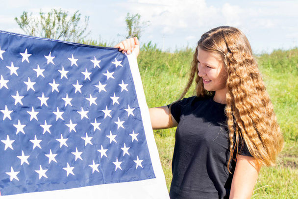 Young girl with curly hair wrapped in USA Flag in Field. American flag. Patriotic holiday. - Valokuva, kuva