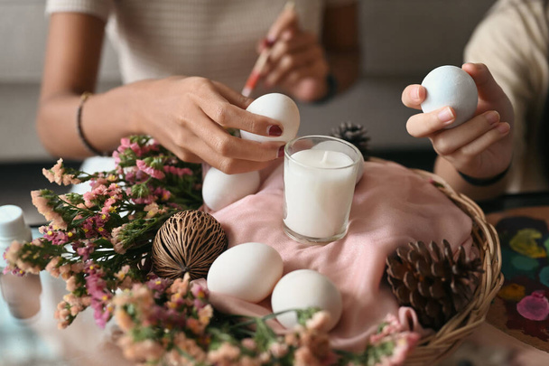 Matka a dcera pořádají velikonoční vajíčka do proutěného koše a připravují se na velikonoční oslavu. - Fotografie, Obrázek