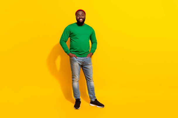 Photo of cheerful positive confident man hands pockets wear red beanie green shirt isolated yellow color background - Фото, изображение