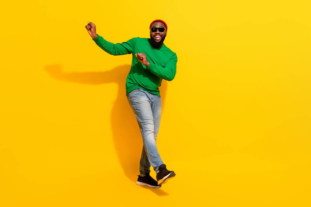 Photo of carefree positive clubber man dance wear sunglass red beanie green shirt isolated yellow color background - Φωτογραφία, εικόνα