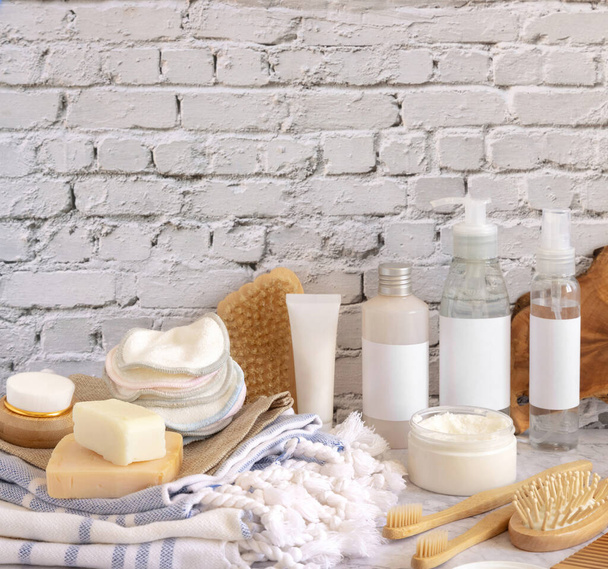Σπιτικά καλλυντικά περιποίησης δέρματος και αξεσουάρ μπάνιου ενάντια σε λευκό τοίχο από τούβλα κοντά. Διακόσμηση συσκευασίας μάρκας. Προϊόντα βιολογικής ομορφιάς. Home Spa concep - Φωτογραφία, εικόνα