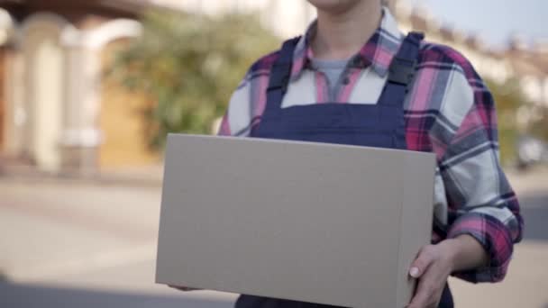 Mensajería femenina sonriente caminando con caja de cartón - Metraje, vídeo