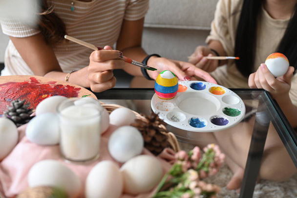 Child and mother hand painting Easter egg with paintbrush. Easter holidays and people concept. - Foto, Imagen