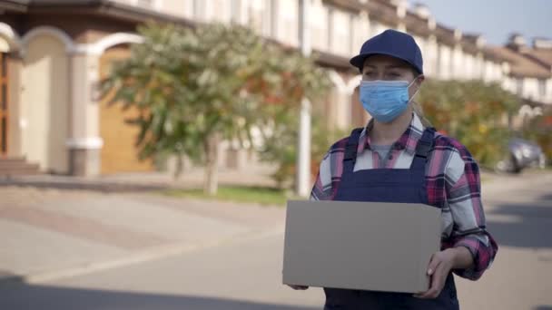 Enmascarado mensajero femenino que lleva caja de cartón - Metraje, vídeo