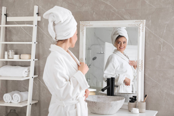 Beautiful woman looking at herself in bathroom mirror - Photo, Image