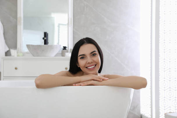 Beautiful young woman relaxing in bathtub at home - Fotoğraf, Görsel