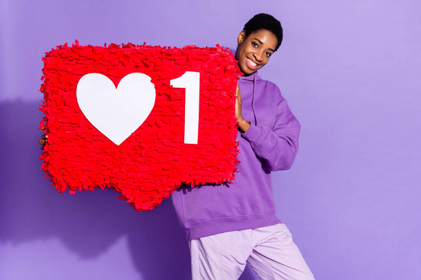 Photo of popular influencer transgender person hold like pinata wear hoodie isolated violet color background - 写真・画像