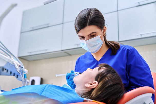 Doctor dentist treats teeth to a young teenage female patient - Φωτογραφία, εικόνα