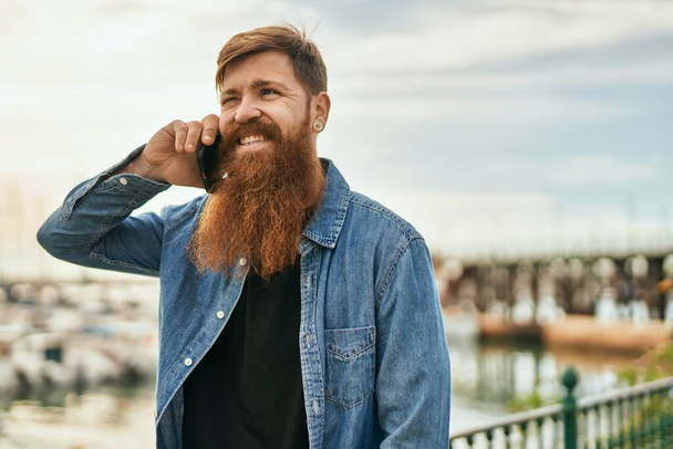 Genç İrlandalı gülümseyen mutlu bir adam şehirdeki akıllı telefondan konuşuyor.. - Fotoğraf, Görsel