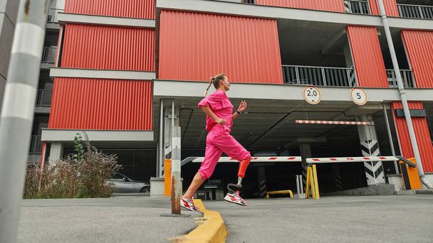 Sports girl with artificial leg run near parking - Photo, image
