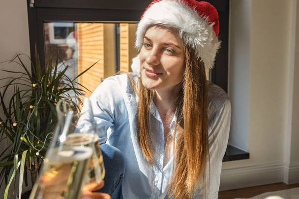 Una ragazza carina in un cappello di Capodanno clinks un bicchiere con un amico o fidanzata. Anno nuovo o celebrazione di Natale con gli amici. - Foto, immagini