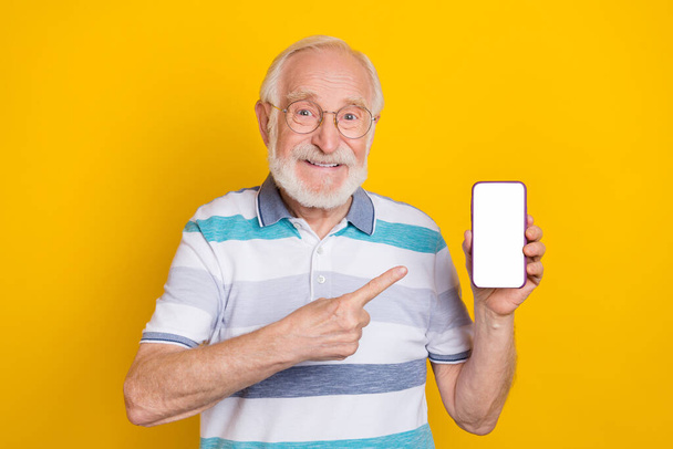 Portrait of attractive cheerful grey haired man showing display copy space app isolated over bright yellow color background - Fotografie, Obrázek