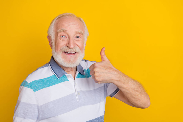 Portrait of attractive cheerful friendly grey haired man showing thumbup ad agree isolated over vibrant yellow color background - Fotó, kép