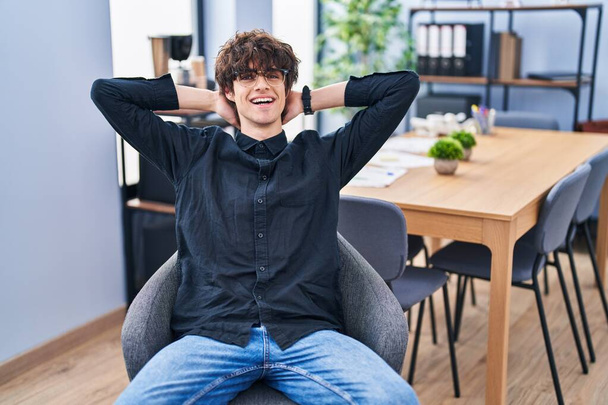 Joven trabajador de negocios hispano relajado con las manos en la cabeza en la oficina - Foto, imagen
