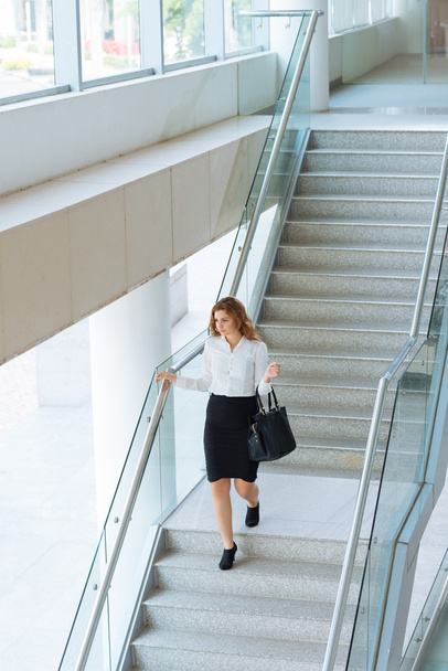 Businesswoman walking downstairs in office building - Foto, afbeelding