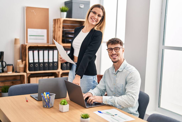 Молодой человек и женщина бизнес-работники с помощью ноутбука, работающего в офисе - Фото, изображение