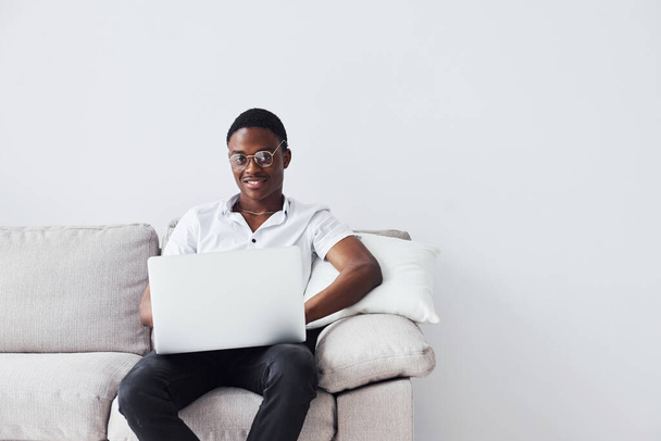 Young african american man in formal clothes sitting indoors with laptop in hands. - Φωτογραφία, εικόνα
